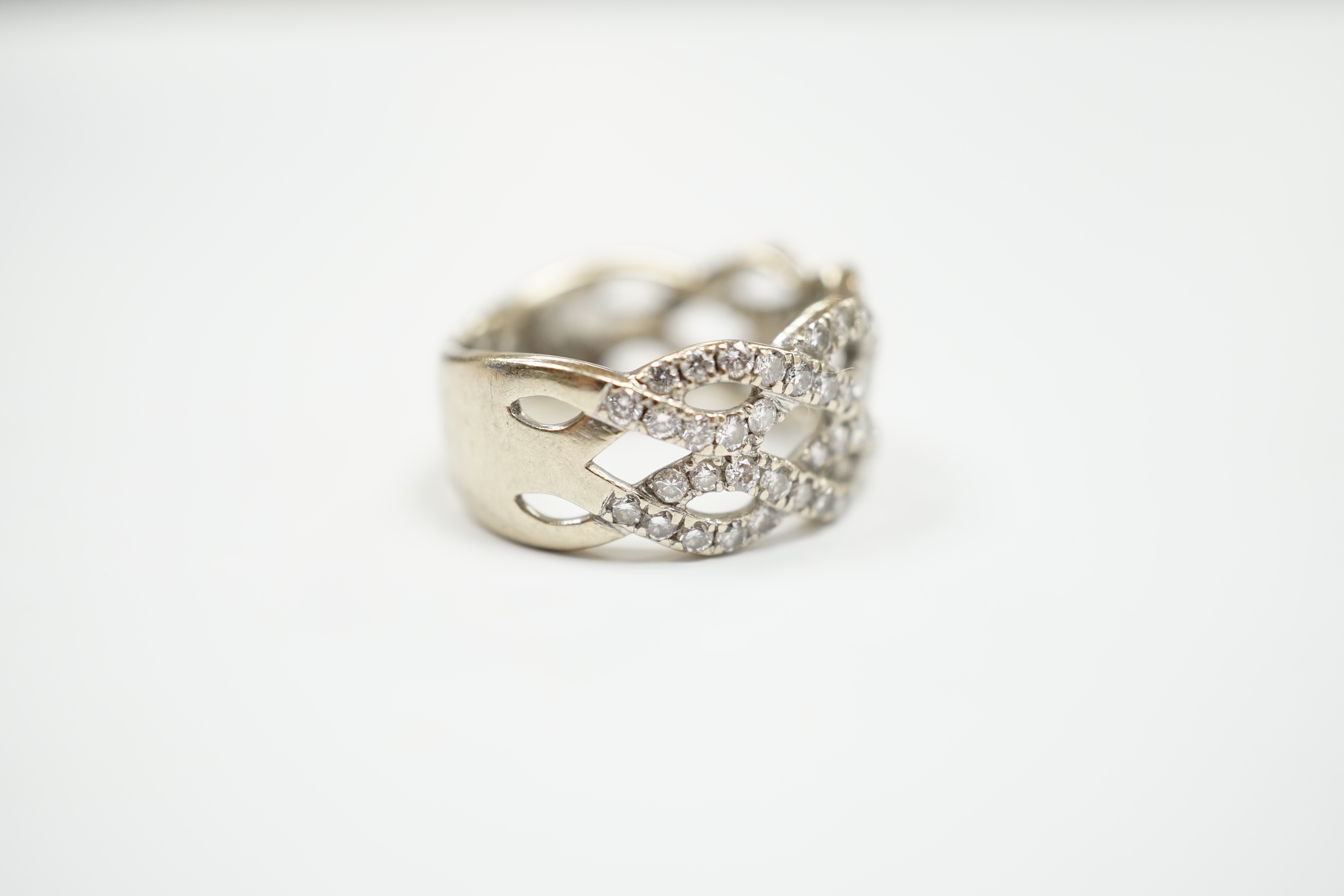 A modern 14k white metal and diamond chip cluster set dress ring, of interwoven design, size M, gross weight 6.4 grams.